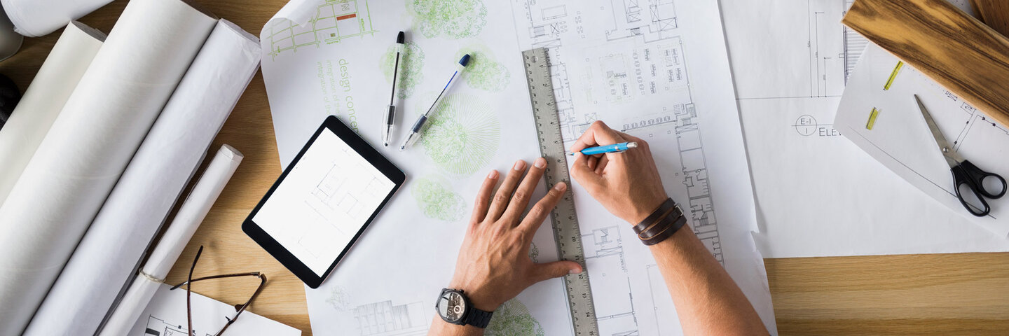 Overhead view architect drafting blueprints at table