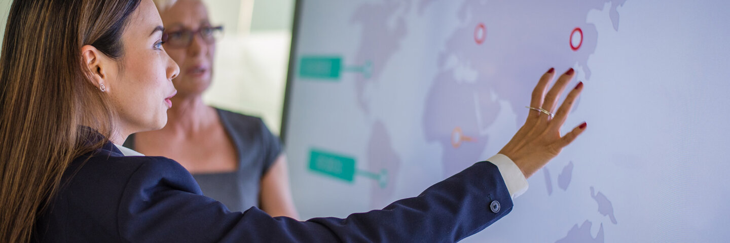two business women looking at world map