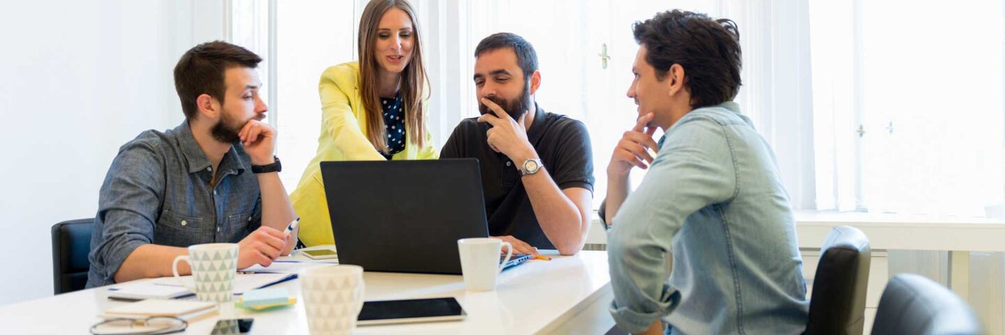 Coworkers reviewing laptop in a conference room.