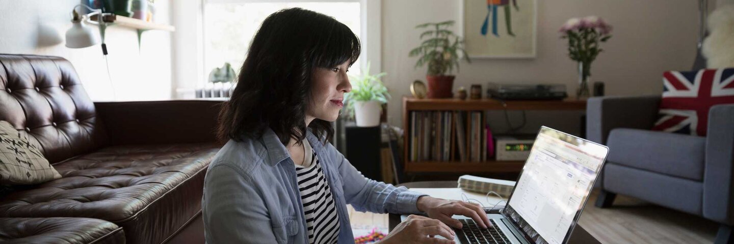 Woman enrolling on laptop in living room.