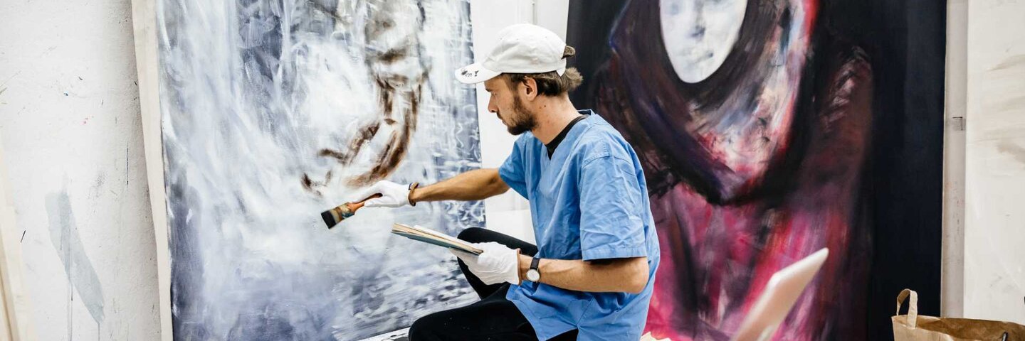Young artist working on a big painting in his atelier