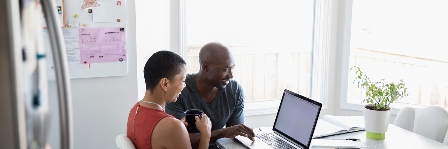 couple looking at a laptop screen at their kitchen table