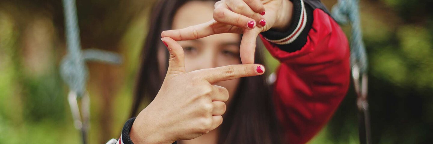 young woman in red making square frame with fingers