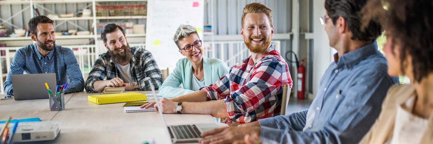 Happy entrepreneur talking to his colleagues on a meeting in a board room.