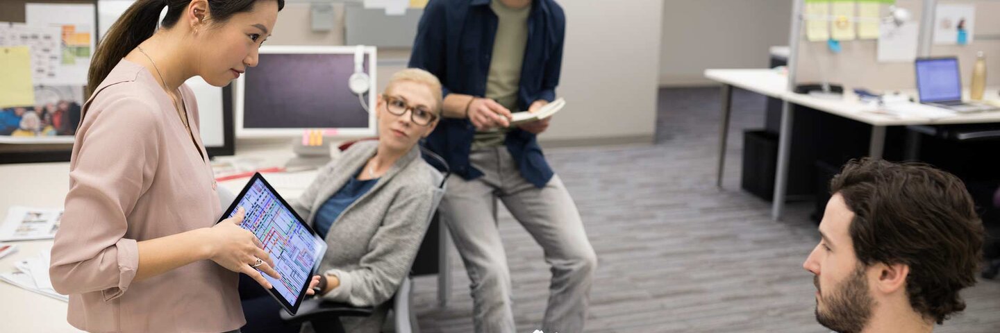 Businesswoman with digital tablet leading meeting at office cubicle