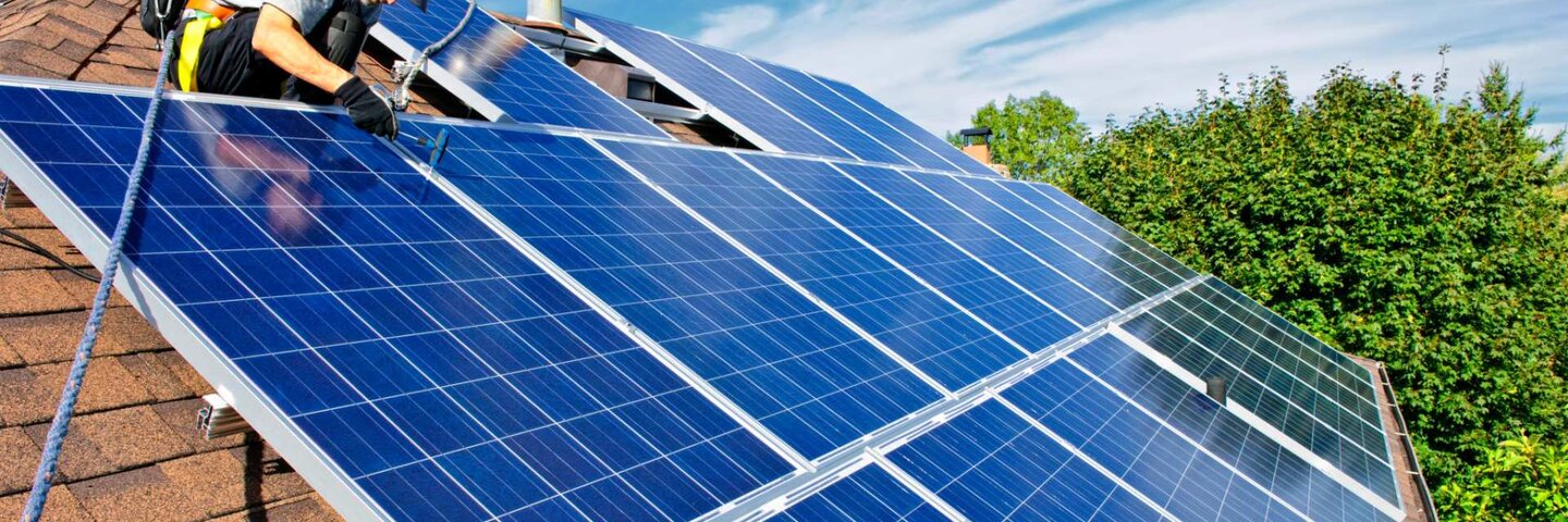 Worker installing solar panels on home roof