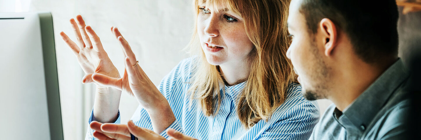 two professionals talking and looking at a computer screen