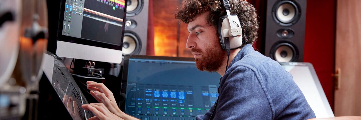 Man working in music studio using computer wearing head phones