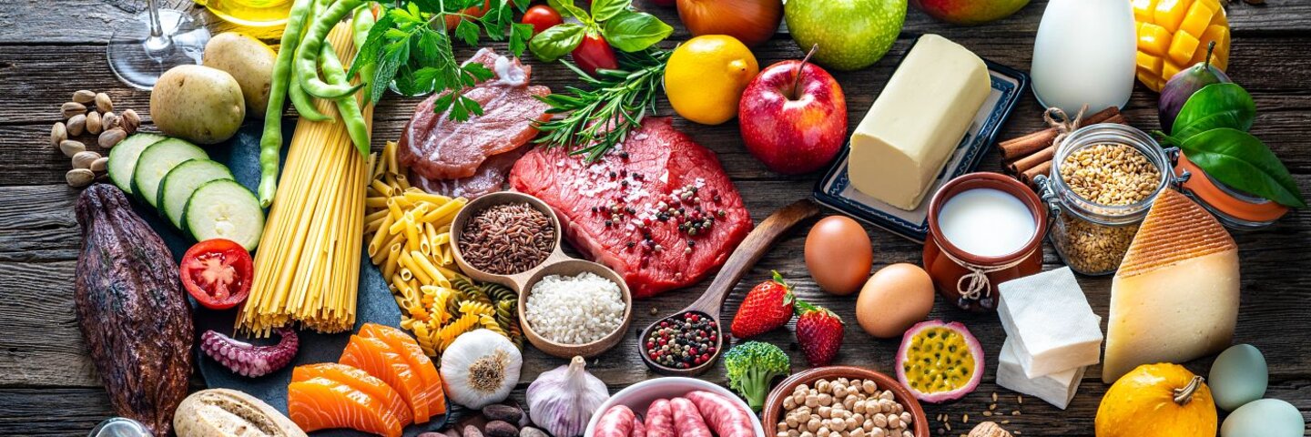 Varied food carbohydrates protein vegetables fruits dairy legumes on wood