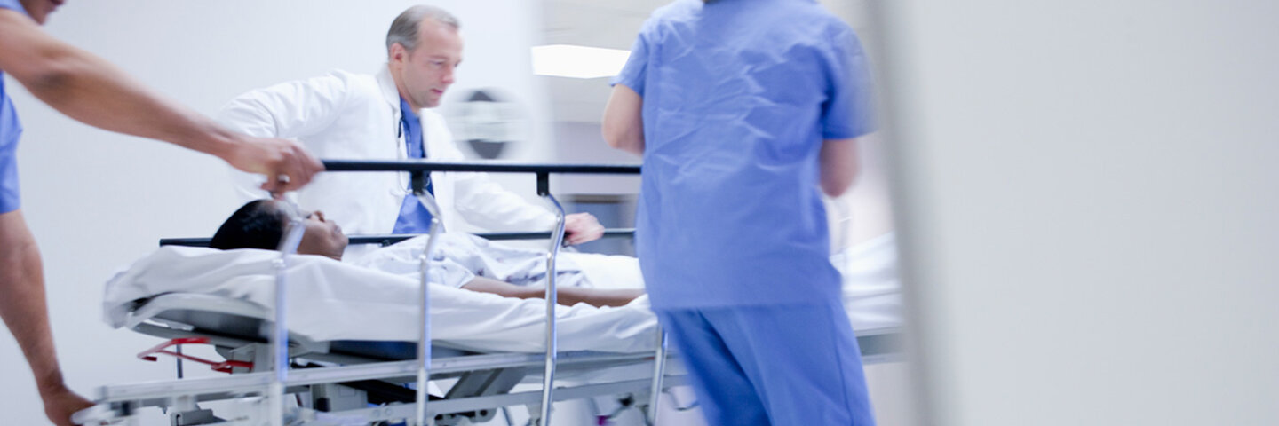 Doctors wheeling in patient to emergency room