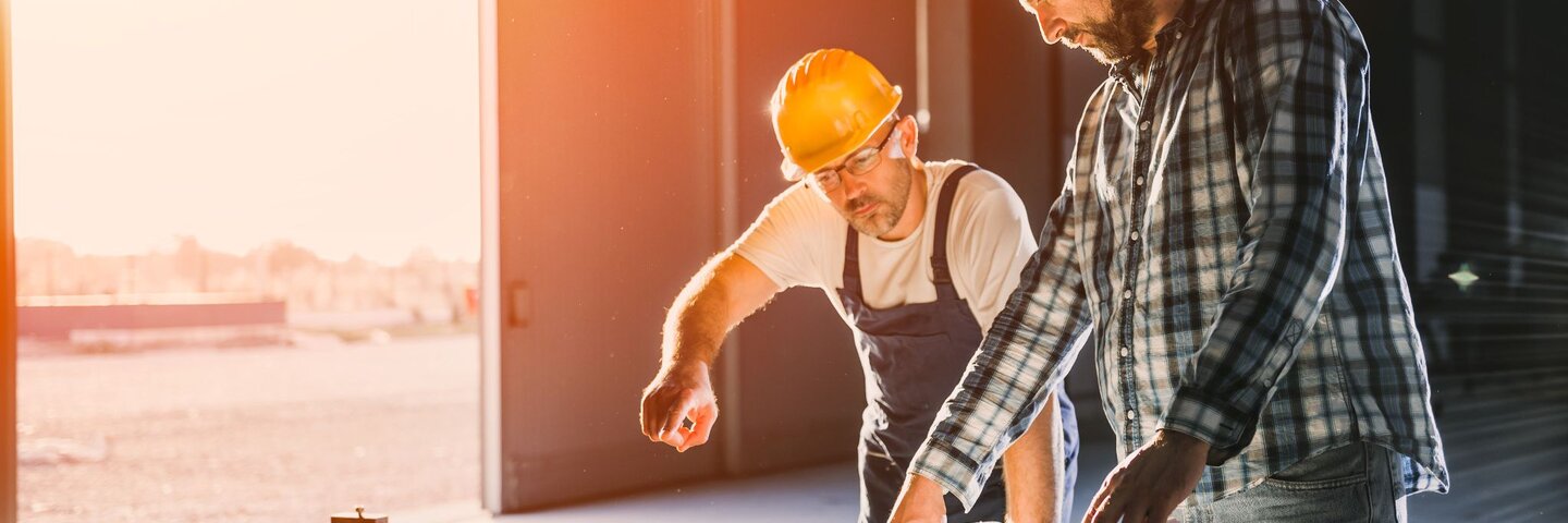 two workers looking over blue prints
