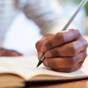 hand holding a pen writing in a notebook