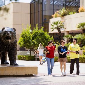 small group of students walking by The Bruin statue on the UCLA campus